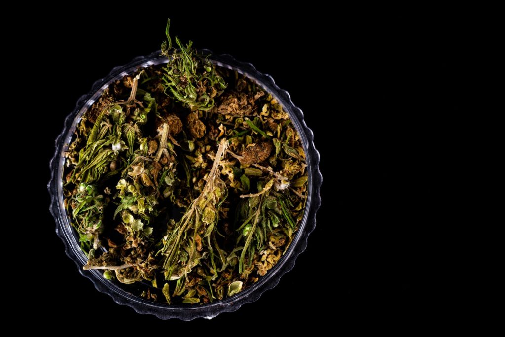 Cannabis Flower Buds in Glass Jar, Top Down Close Up. Dark Background. Medical Marijuana Concept